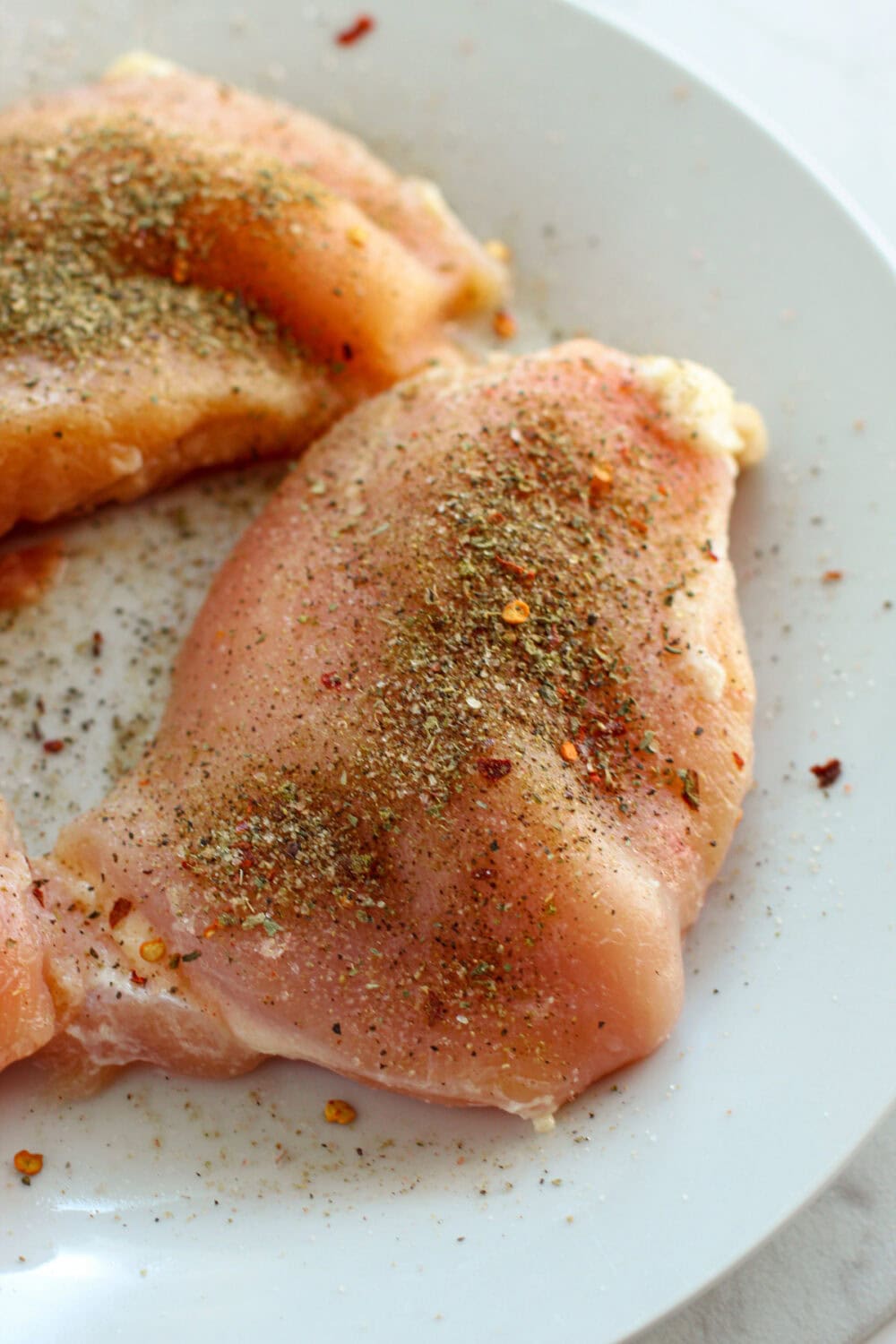 Seasoning on raw chicken breasts.
