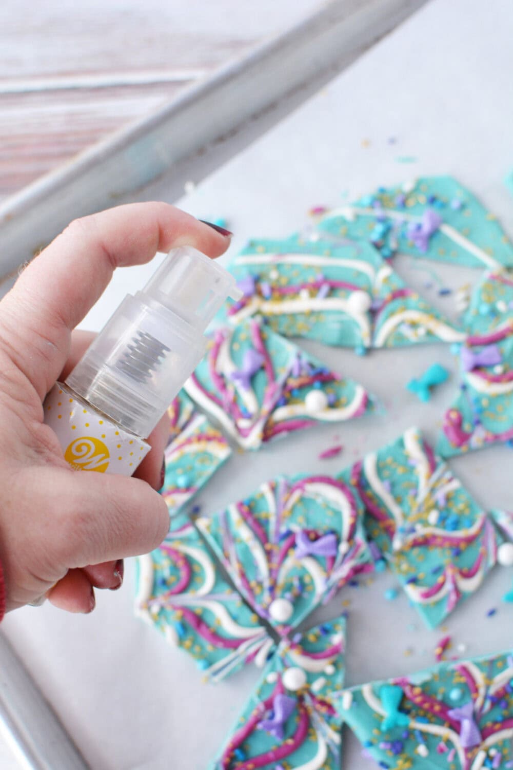 Spraying edible gold glitter onto mermaid candy. 