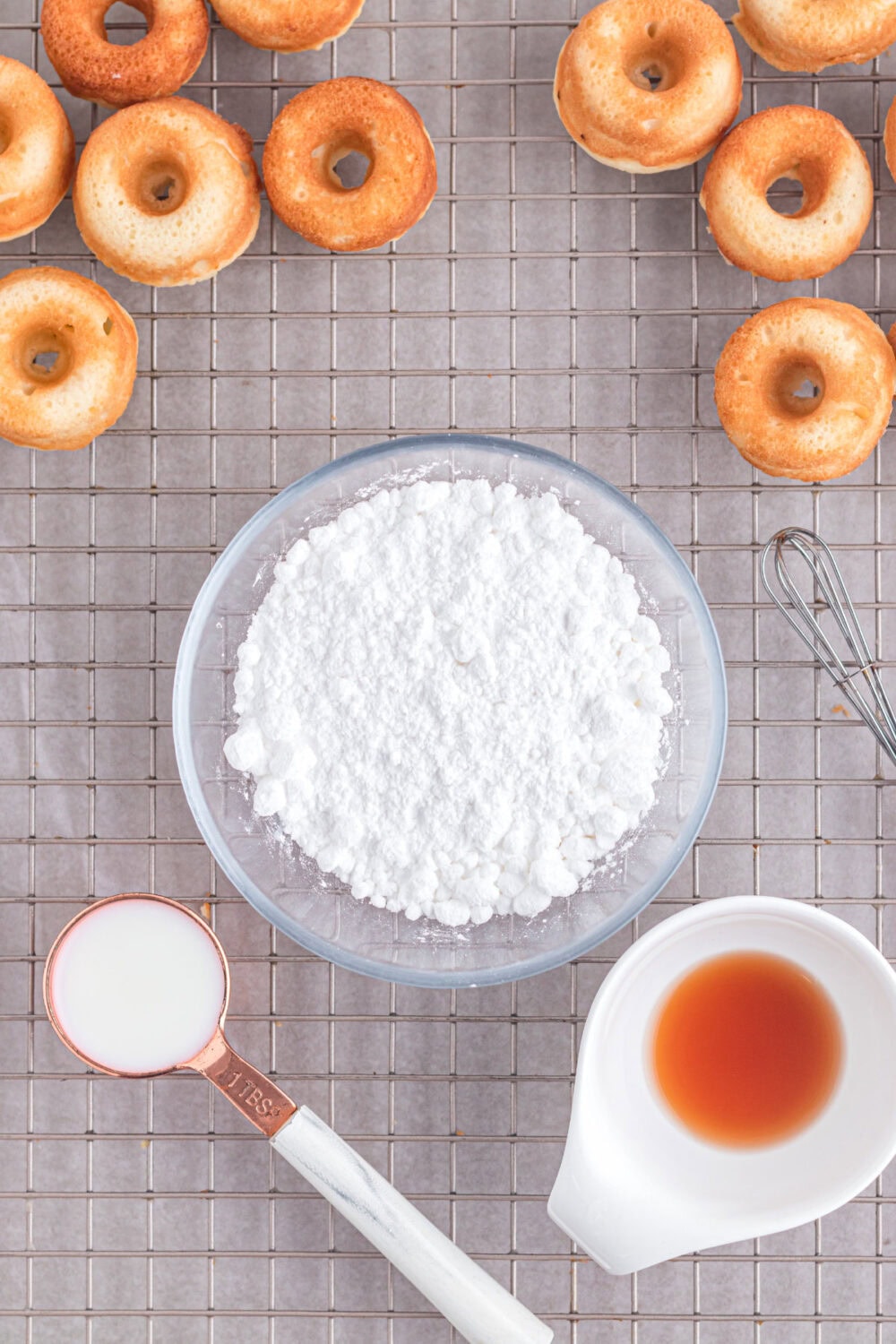 Donuts, powdered sugar, vanilla, and milk in bowls. 
