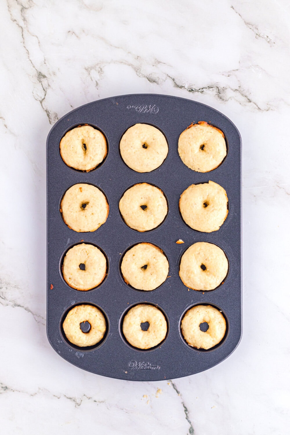 Mini cake donuts in a pan after baking. 