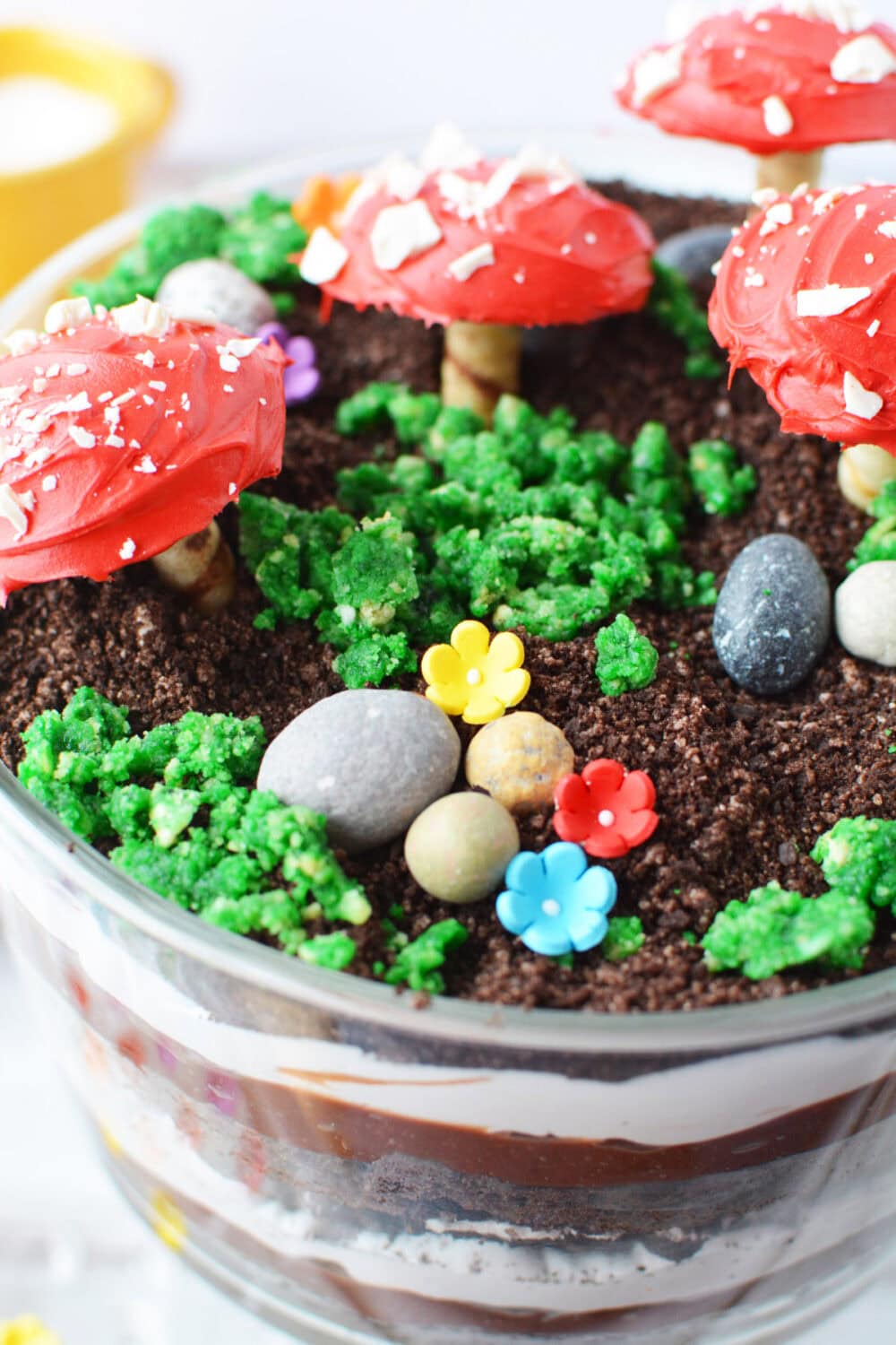 Edible rocks, flowers, and toadstools on top of a trifle. 