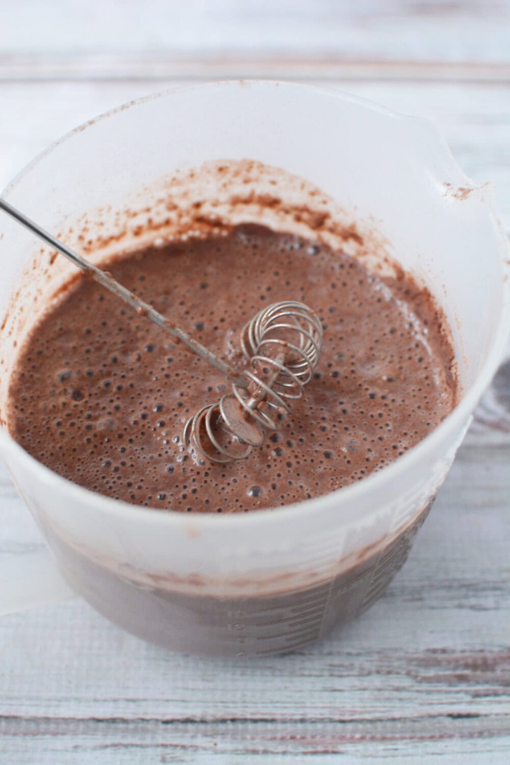 Mixing chocolate pudding in a container.