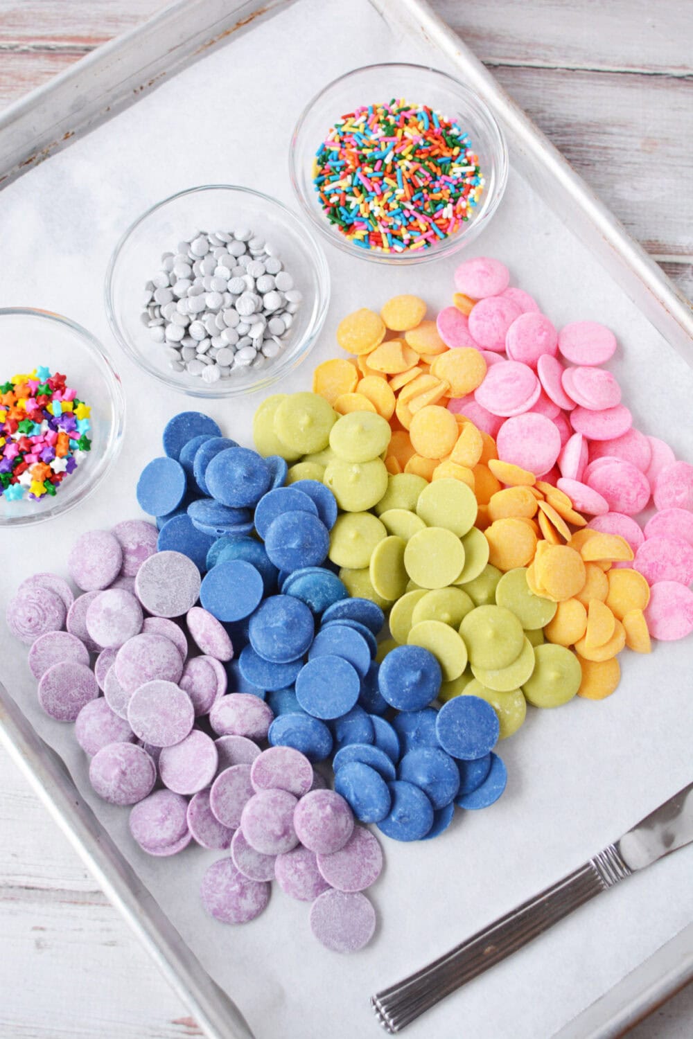 Candy melts and sprinkles lined up on a board. 