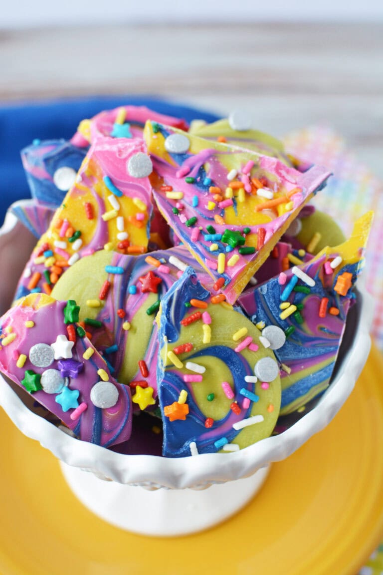 Pieces of rainbow bark candy in a white bowl.