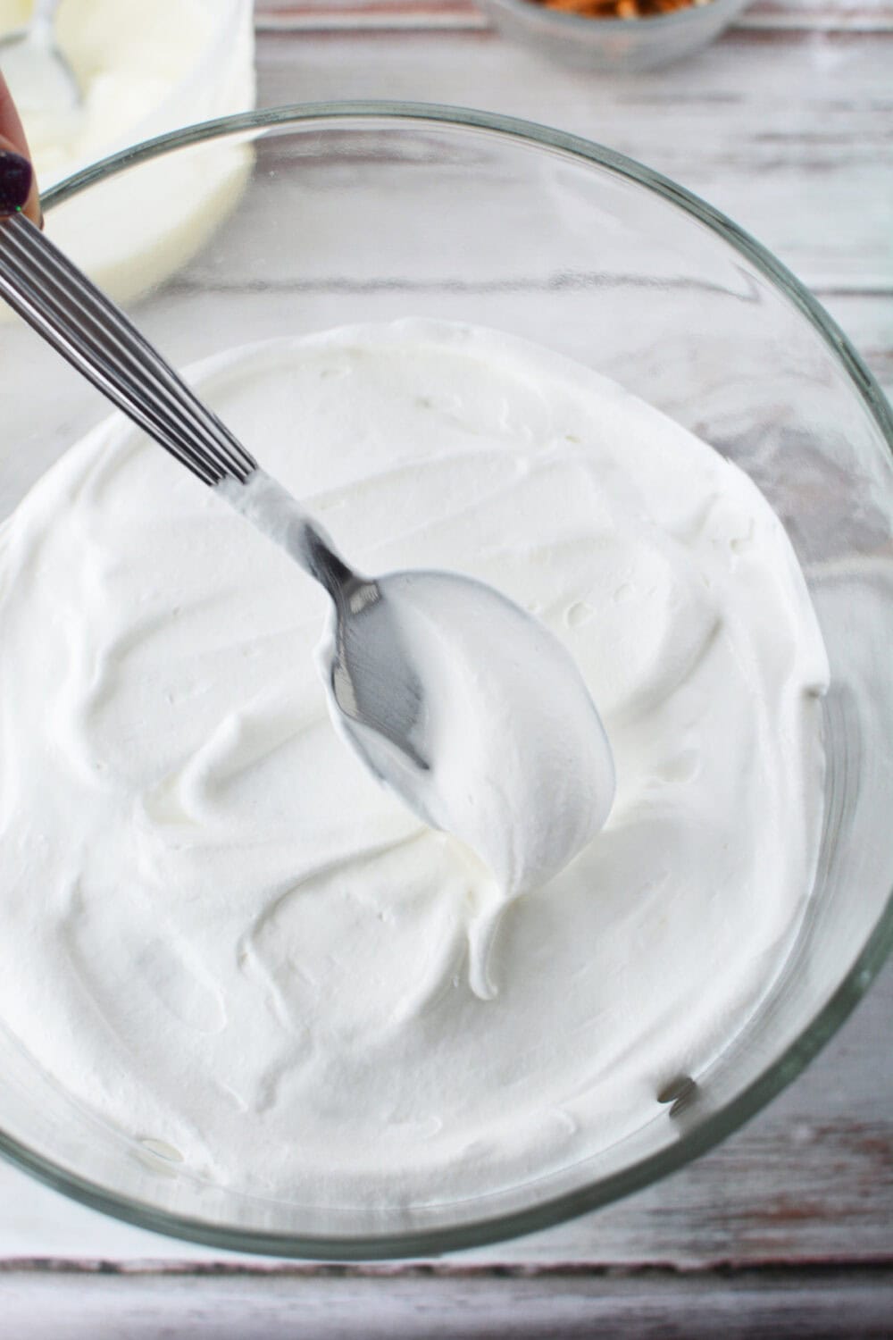 Whipped cream on top of cake and pudding in a trifle dish. 