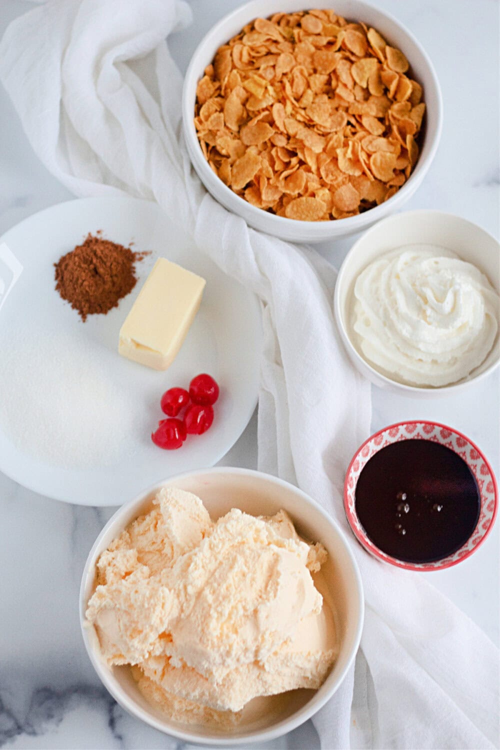 Corn flakes, ice cream, and other ingredients in bowls. 