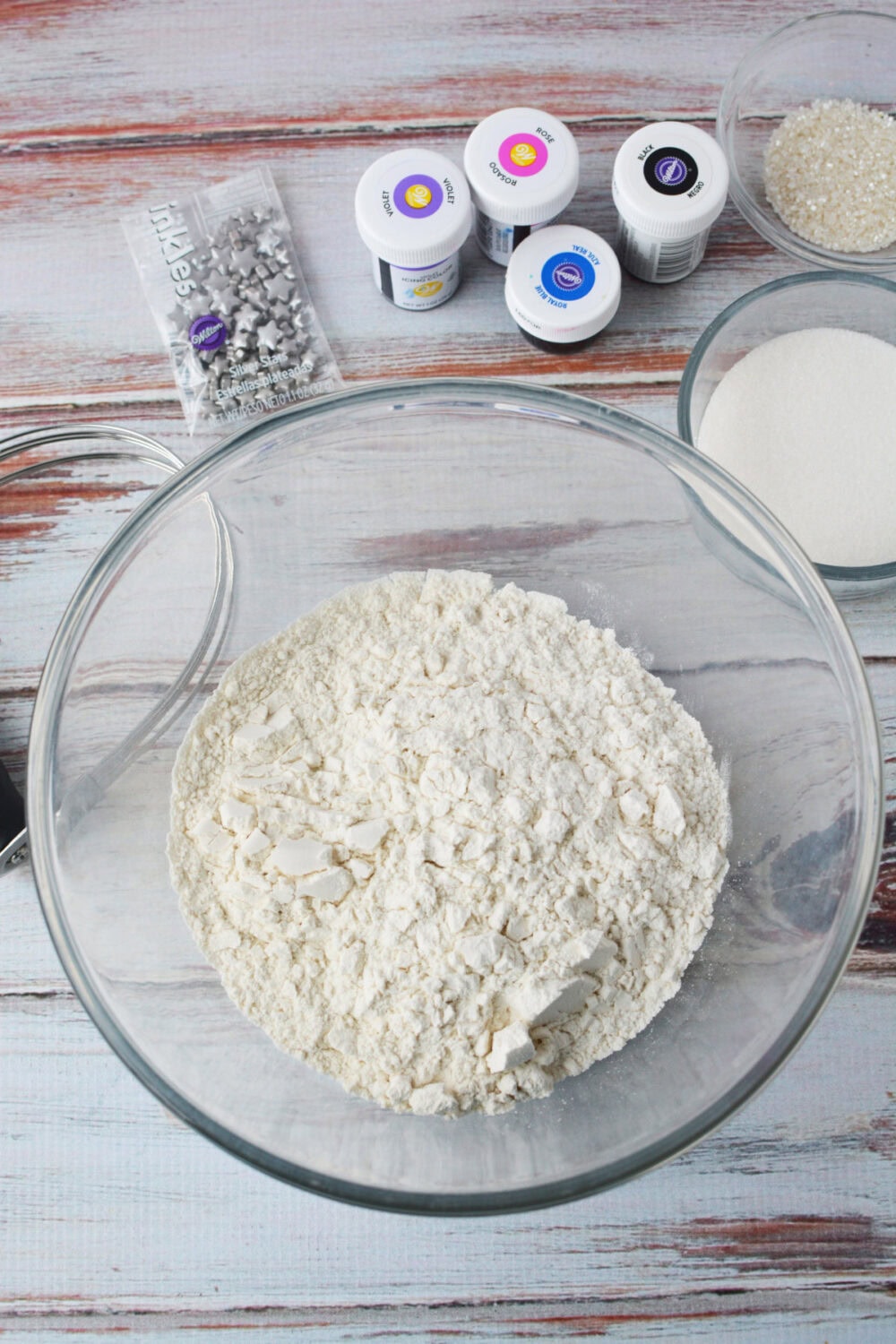 Flour, candy stars, food coloring and sugar in bowls. 