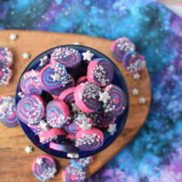 Galaxy shortbread bites in a cup with some on the table.