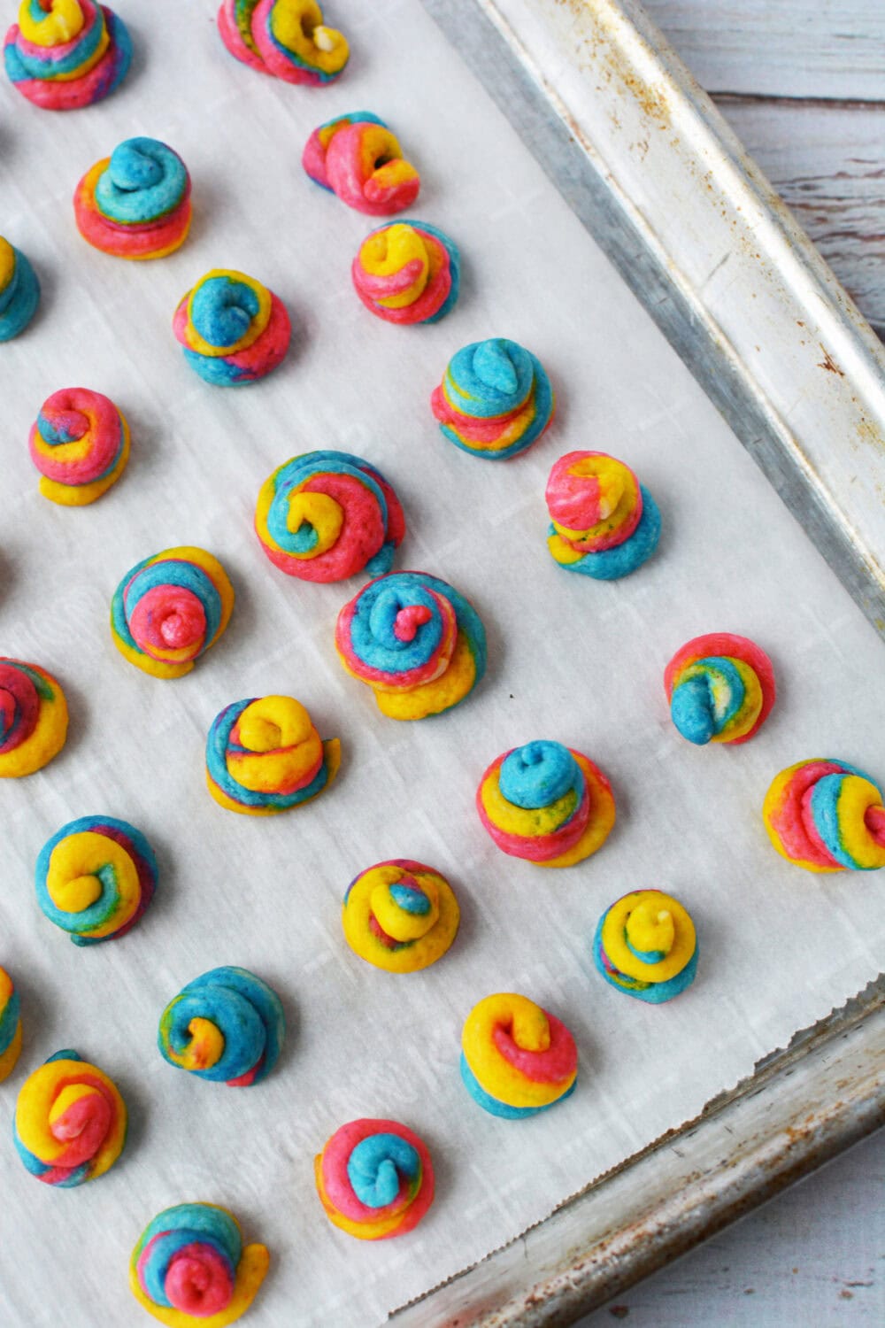 Rainbow unicorn poop dough bites on a baking sheet. 