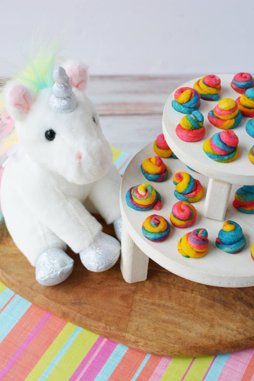Unicorn stuffed animal sitting next to unicorn poop shortbread cookie bites. 