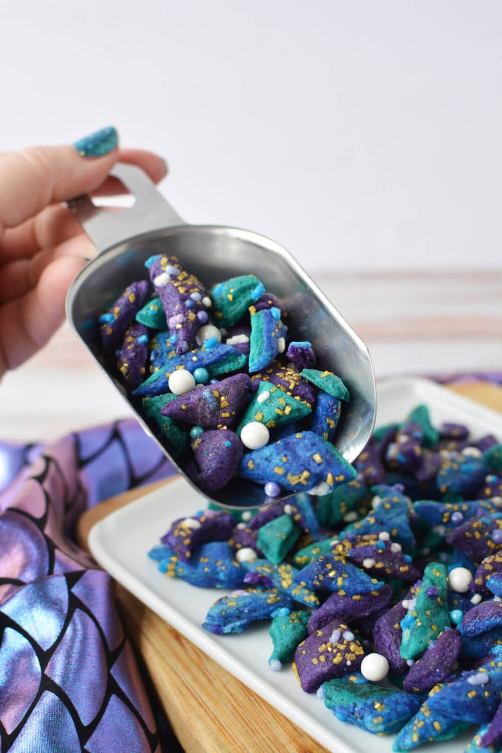 Holding a shovel full of tiny mermaid bites cookies.