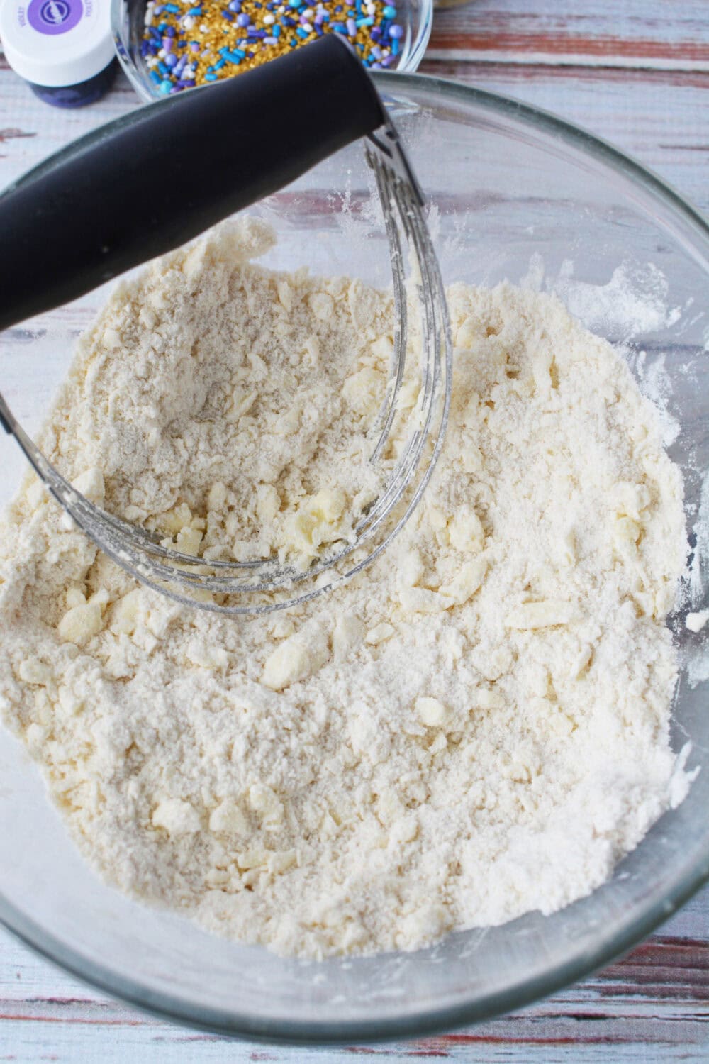 Using a pastry blender to cut butter into flower mixture.