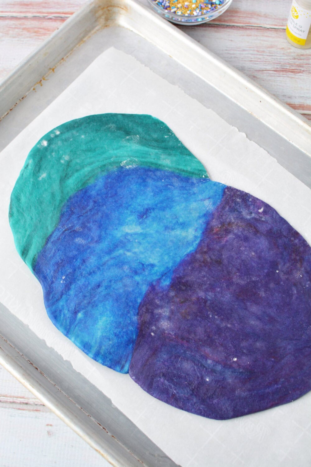 Blue, green, and purple dough flattened.