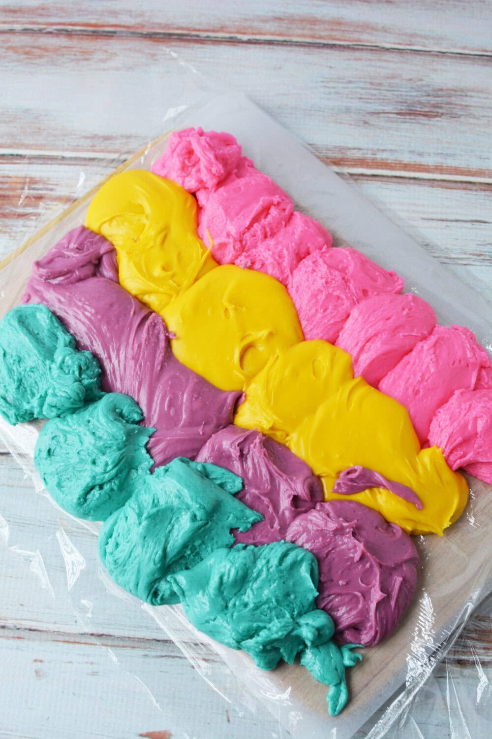 A rainbow of fudge colors on plastic wrap.