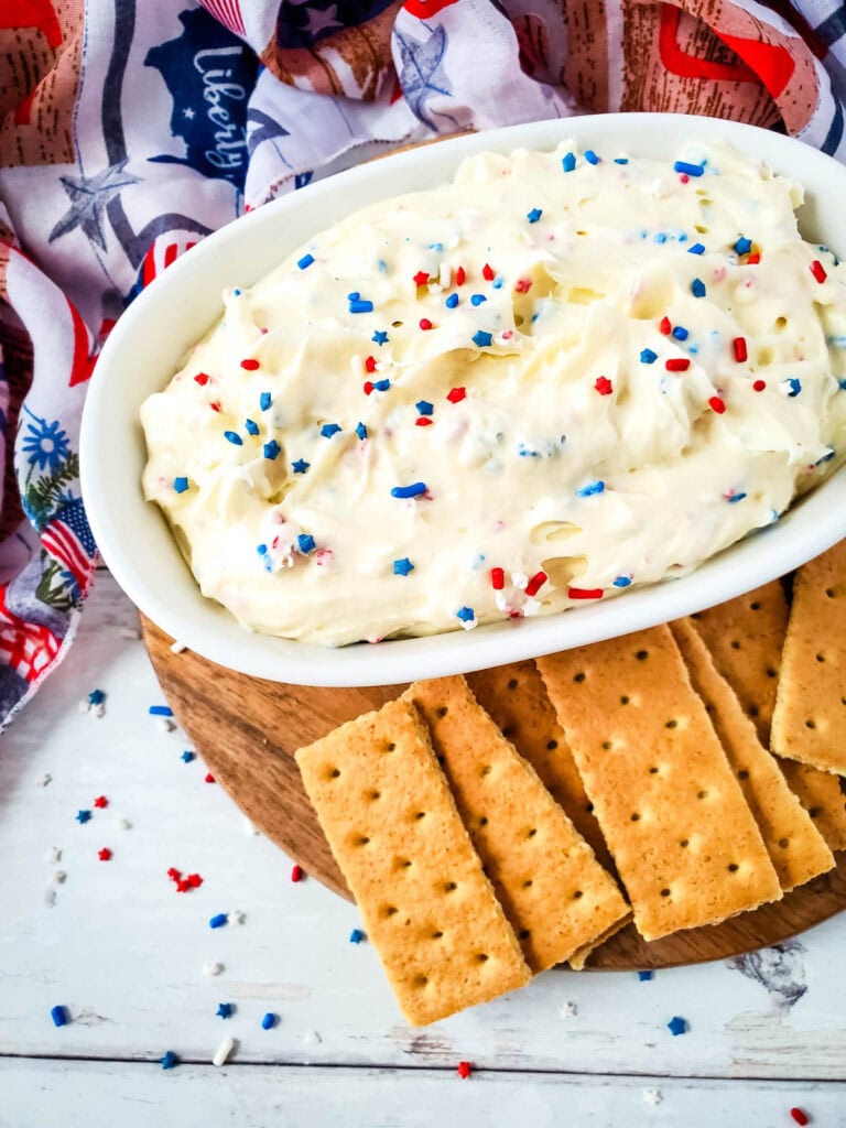Cheesecake dip with red, white, and blue sprinkles, and graham crackers for dipping.