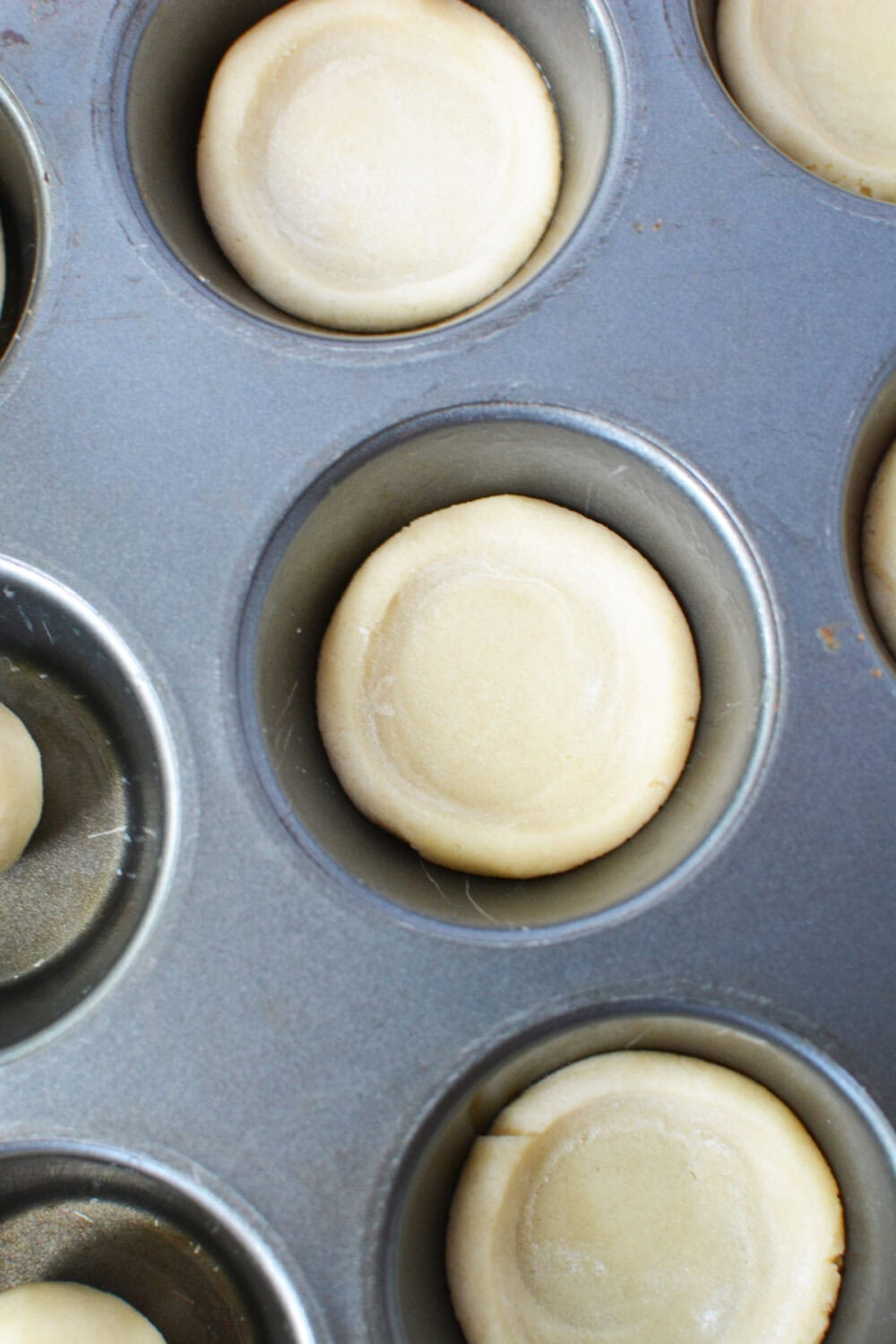 Mini cookie dough pie crusts in a muffin tin.
