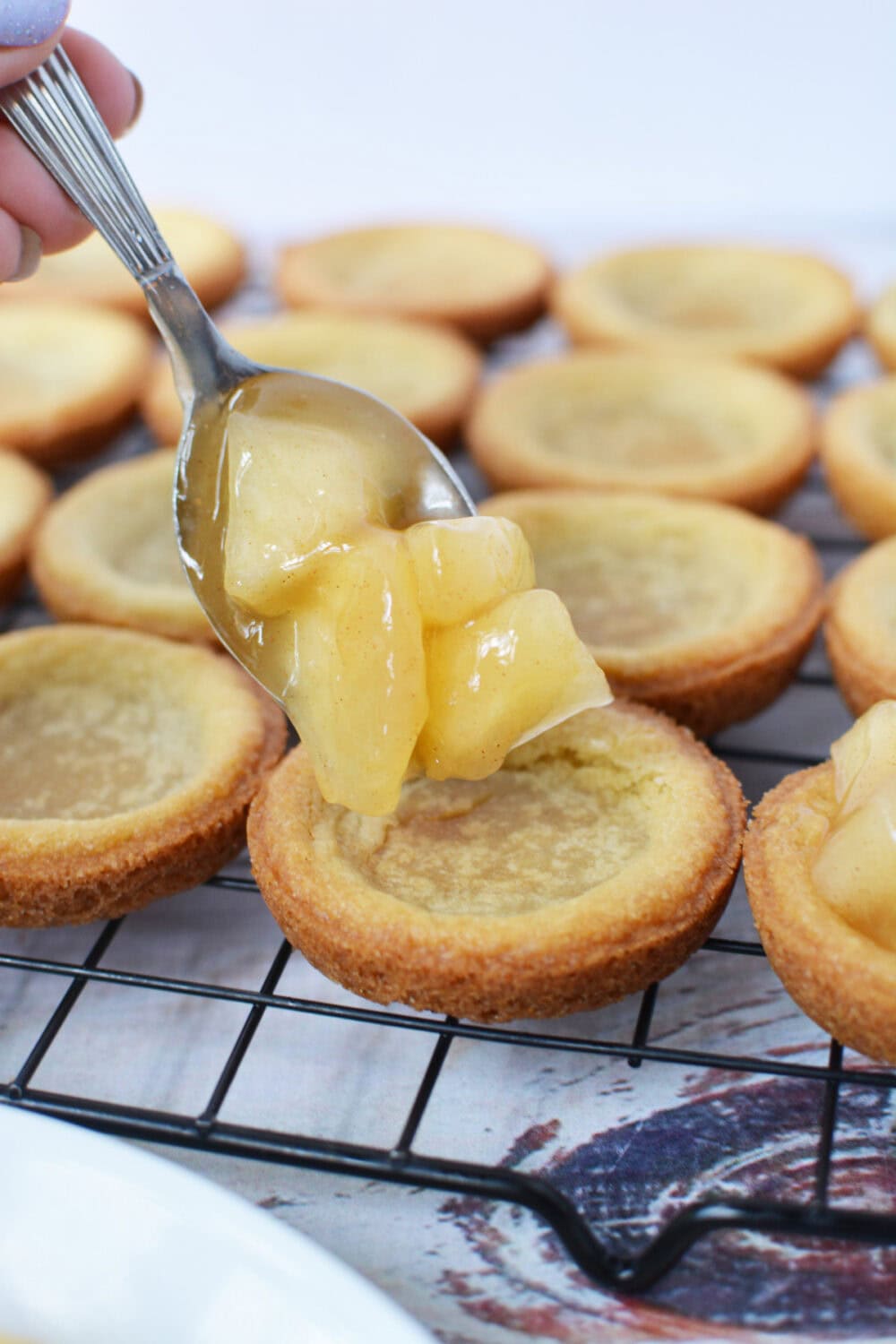 Filling cookie crusts with apple pie filling.