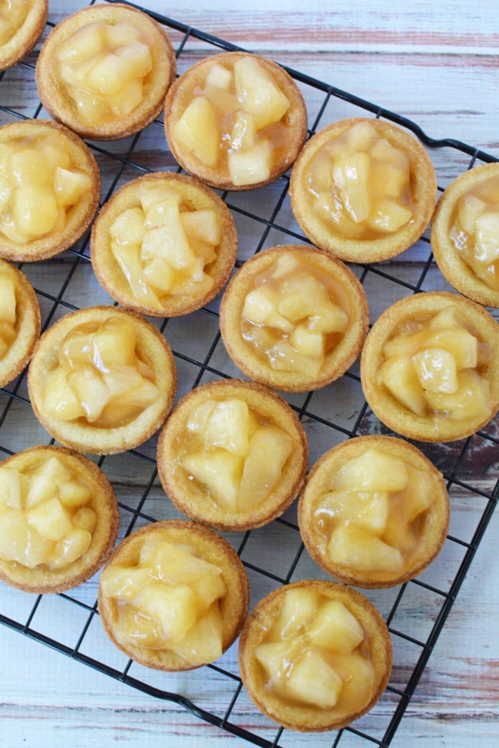 Filled apple pie cookies on a cooling rack.