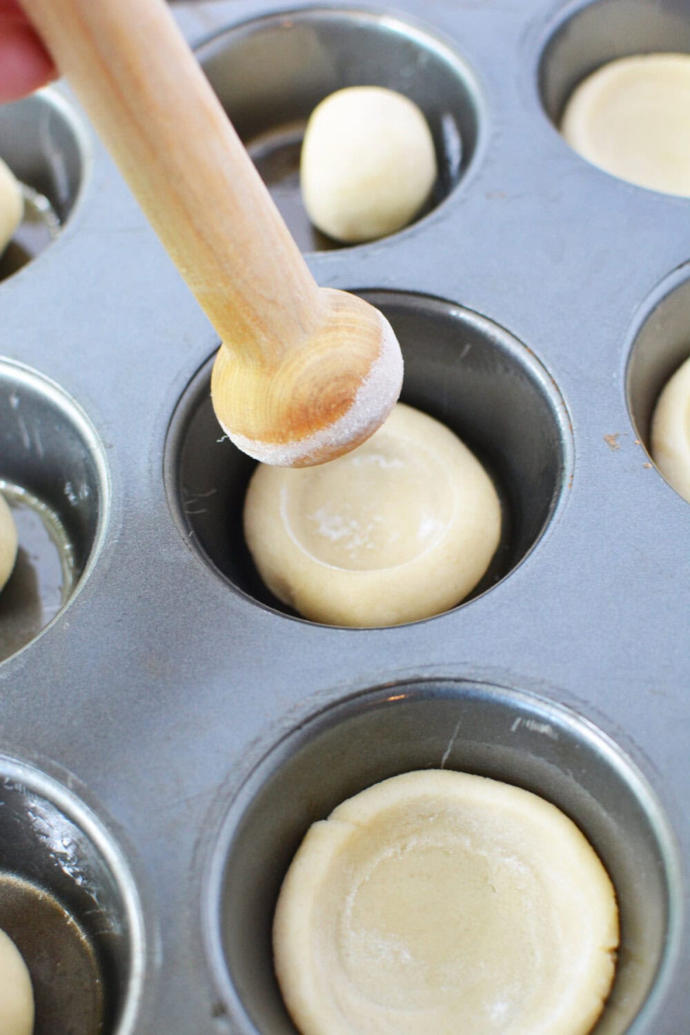 Shaping cookie dough into crusts using a tart shaper.