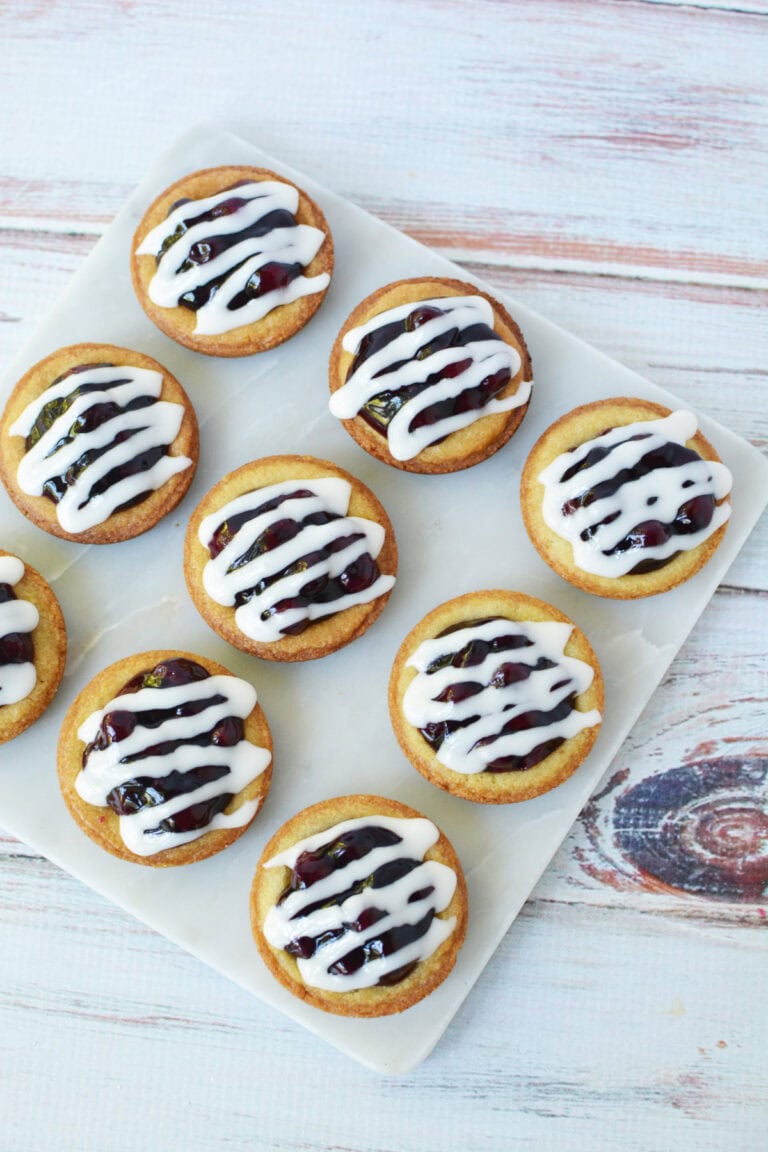 Glazed blueberry pie cookies on a white tray.