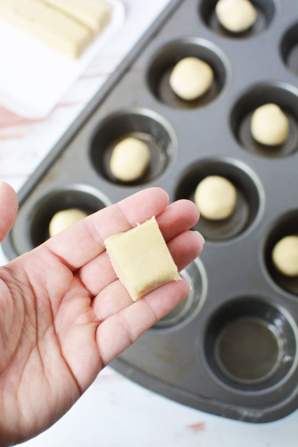 Break and back cookie dough going into a muffin tin.