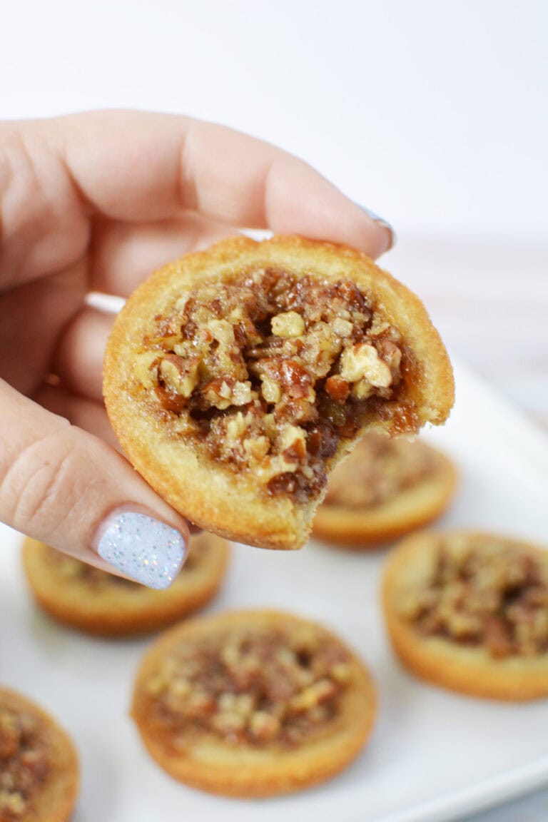 Holding a pecan pie sugar cookie with a bite missing.