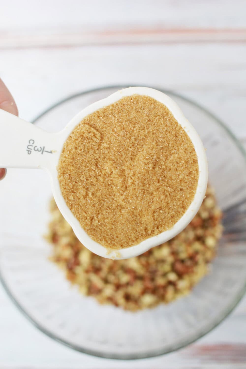 Brown sugar going into bowl with pecans.