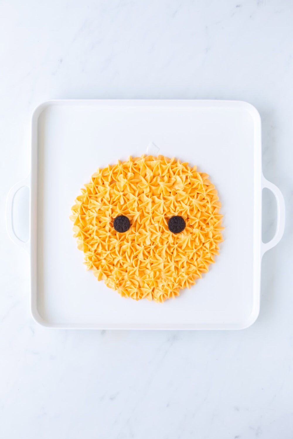 Adding cookie eyes to the frosting pumpkin. 