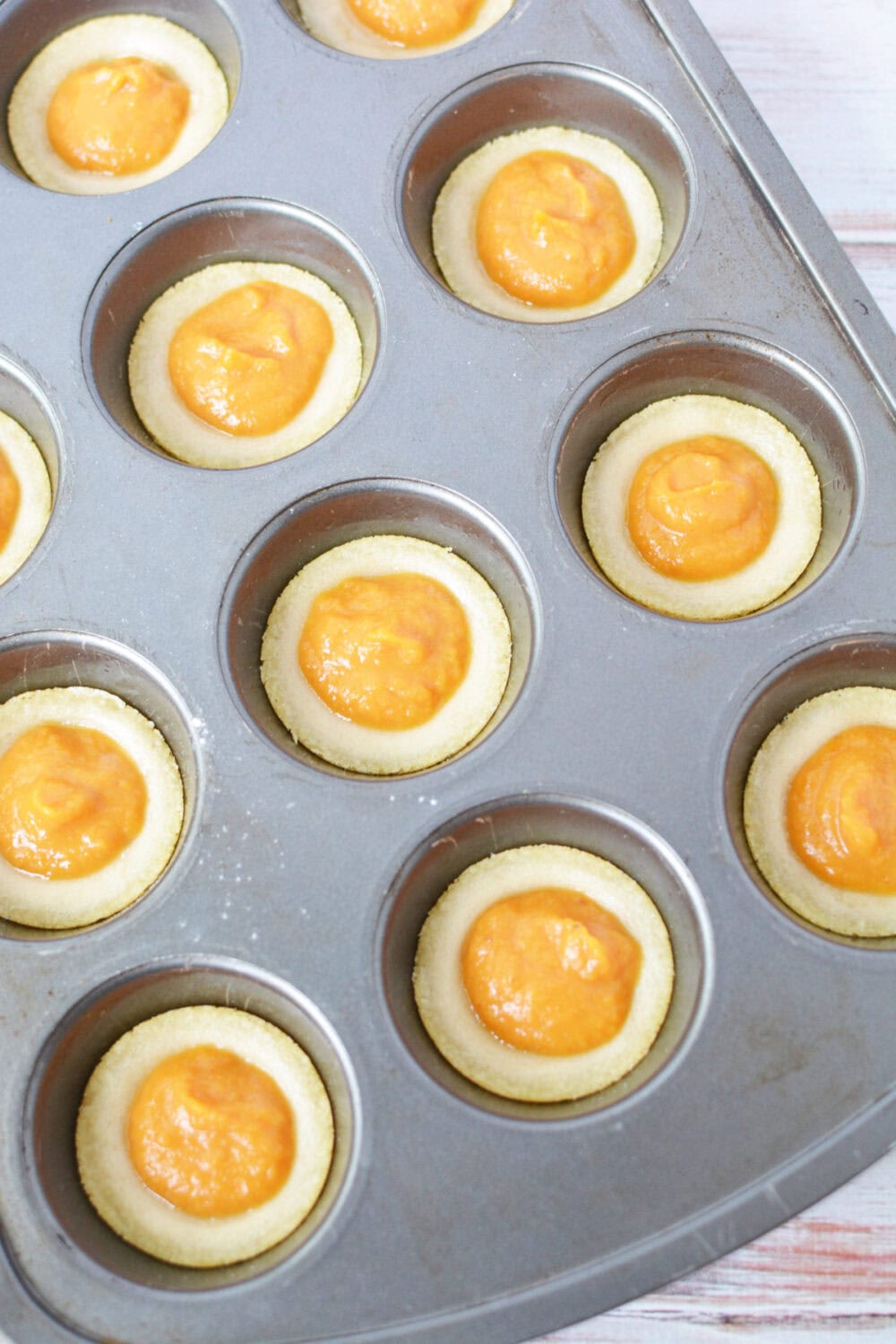 Pumpkin pie filling in cookie crusts in muffin tin.
