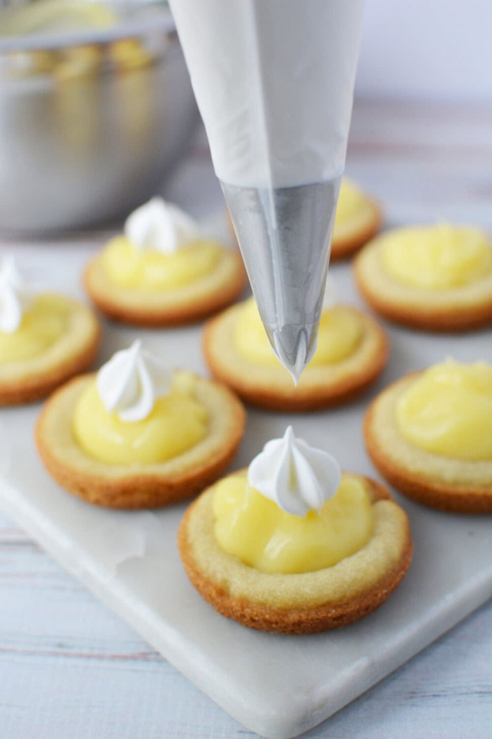 Piping whipped cream on top of banana pudding cookies. 