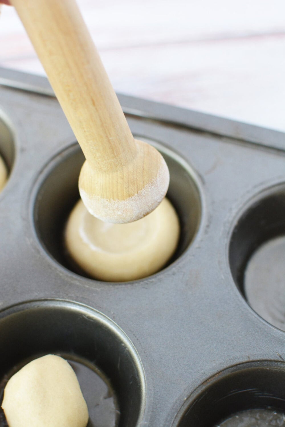 Tart shaper going into a muffin tin. 