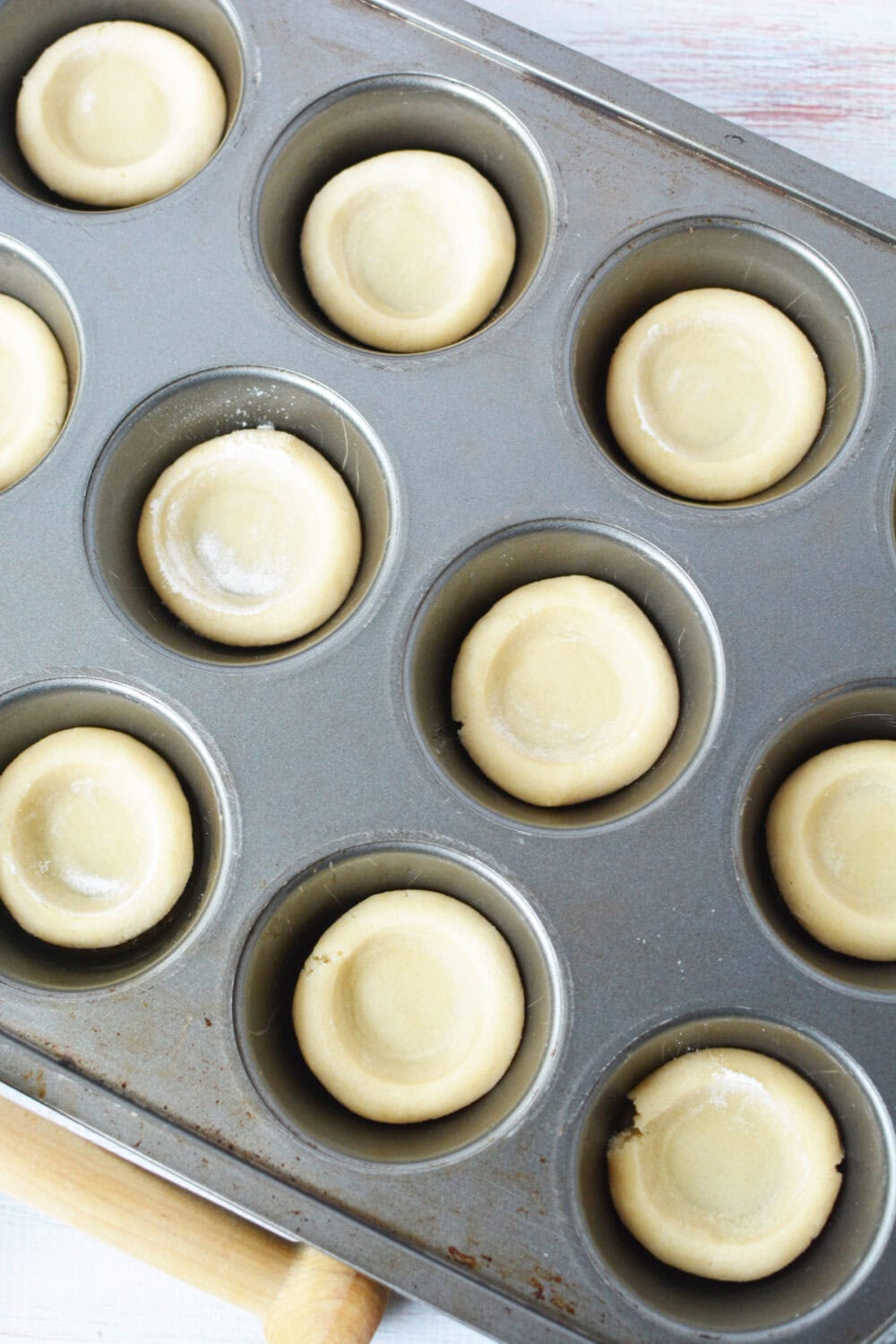 Shaped sugar cookie crusts in a muffin tin. 