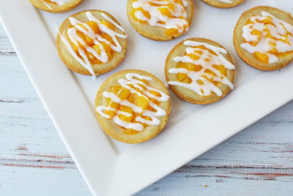 Peach pie cookies topped with glaze on a tray.