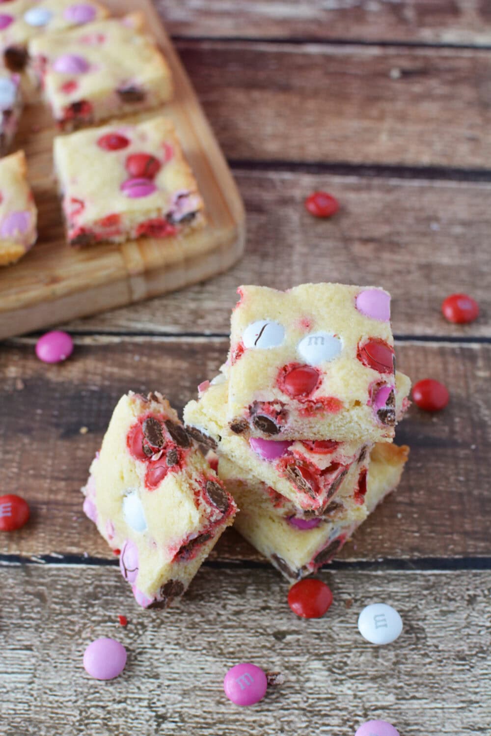 Valentine's Day sugar cookie bars stacked with red, white, and pink M&Ms on the table. 