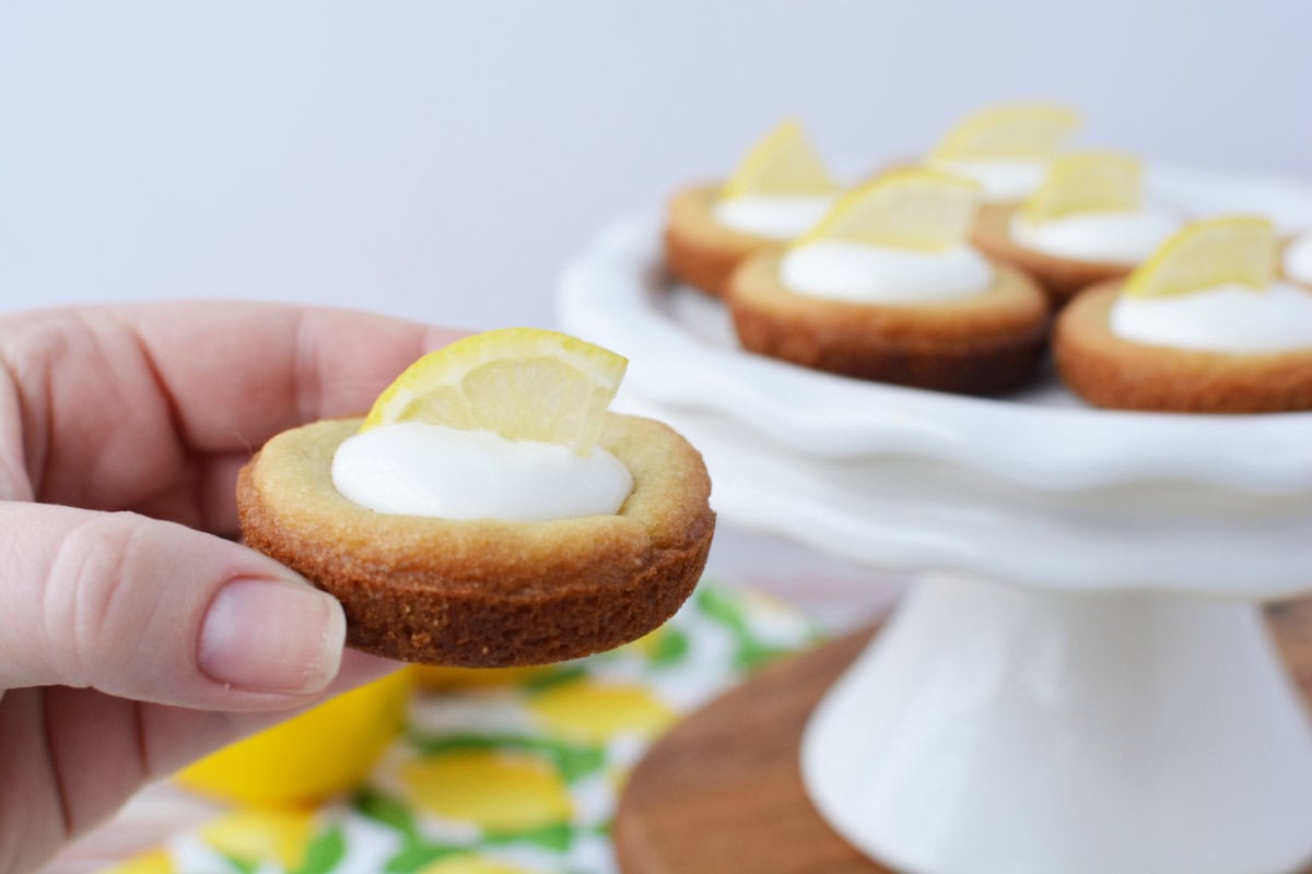 Holding a lemonade pie cookies with the tray in the background.