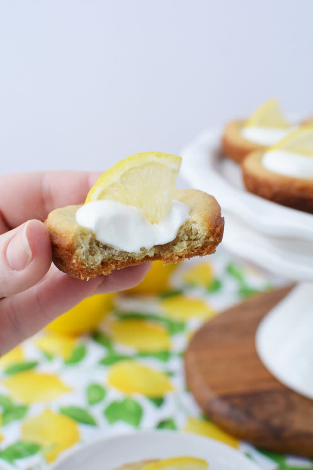 Holding a lemonade sugar cookie with a bite taken out of it. 