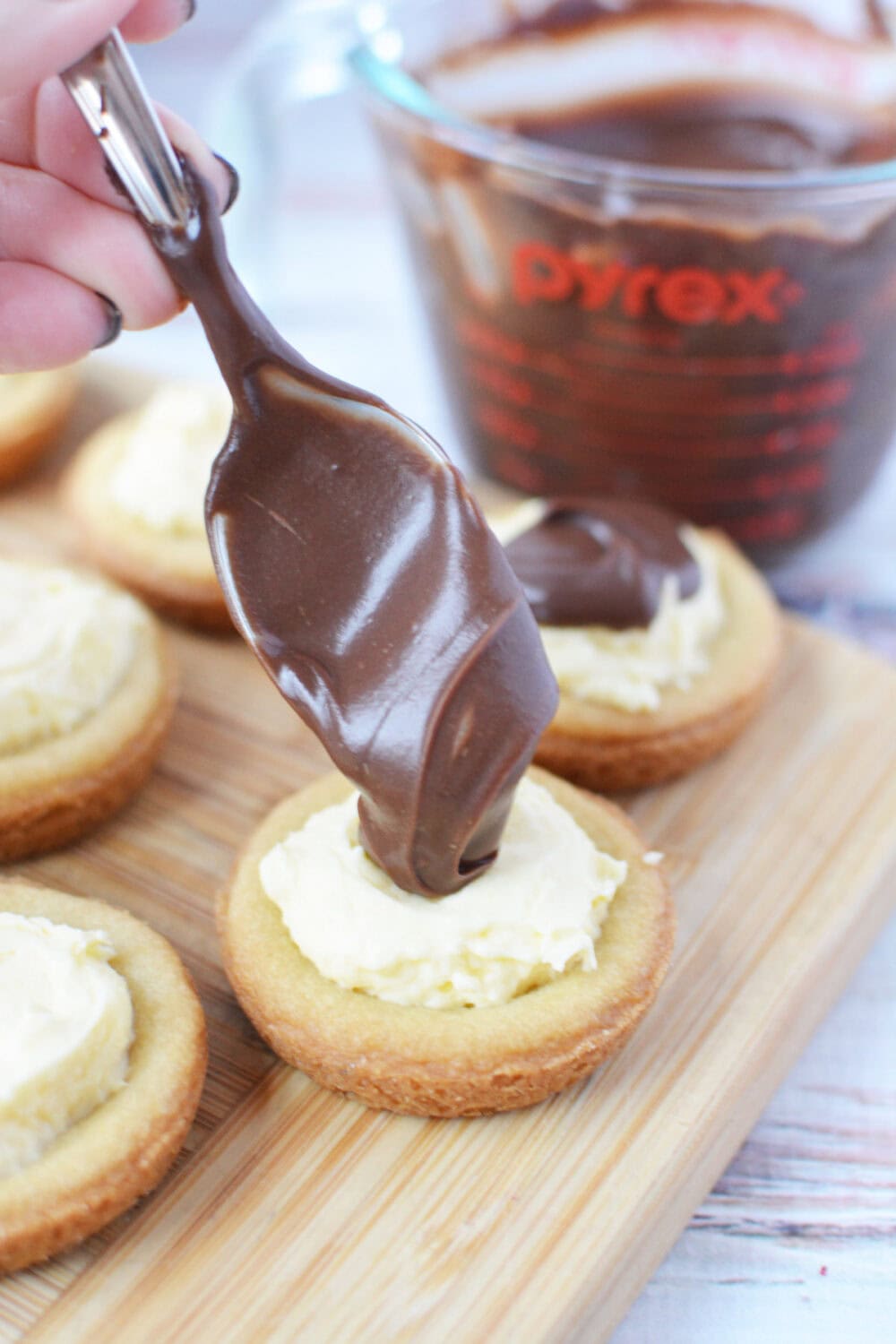 Spooning chocolate ganache onto custard cookies.