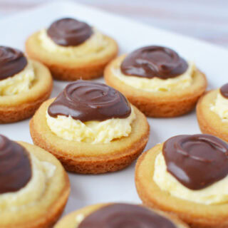 Plate of cream-filled cookies topped with chocolate.