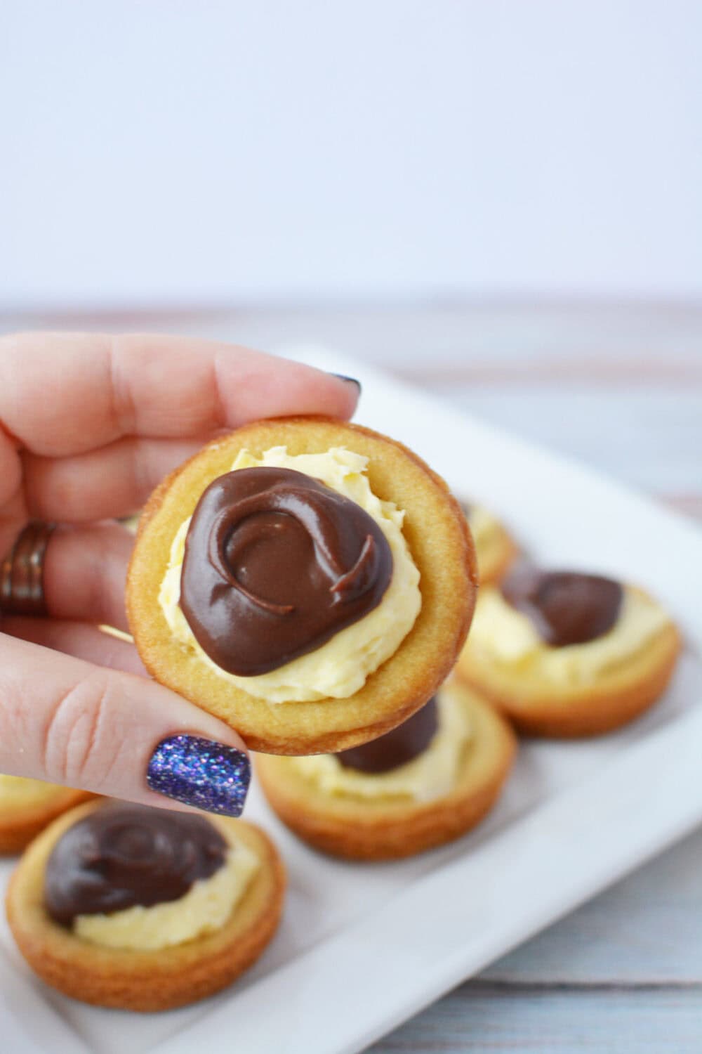 Holding a Boston cream pie cookie over the plate full of them.