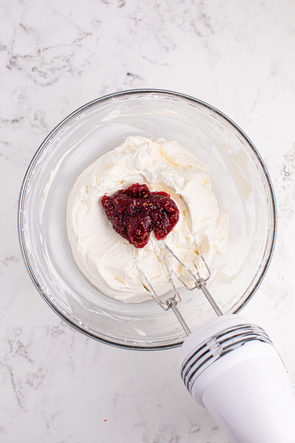 Adding raspberry jam to whipped cream.