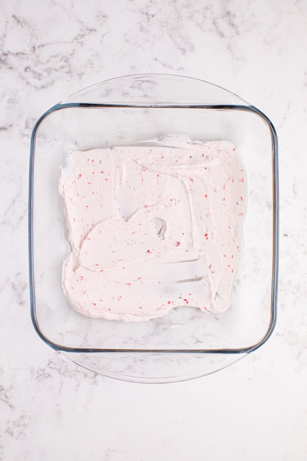 Raspberry whipped cream in the bottom of a glass dish.