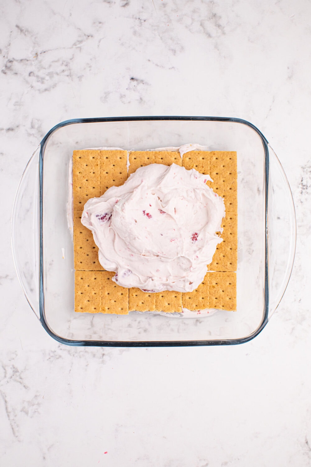 Next layer of raspberry whipped topping on top of graham crackers.