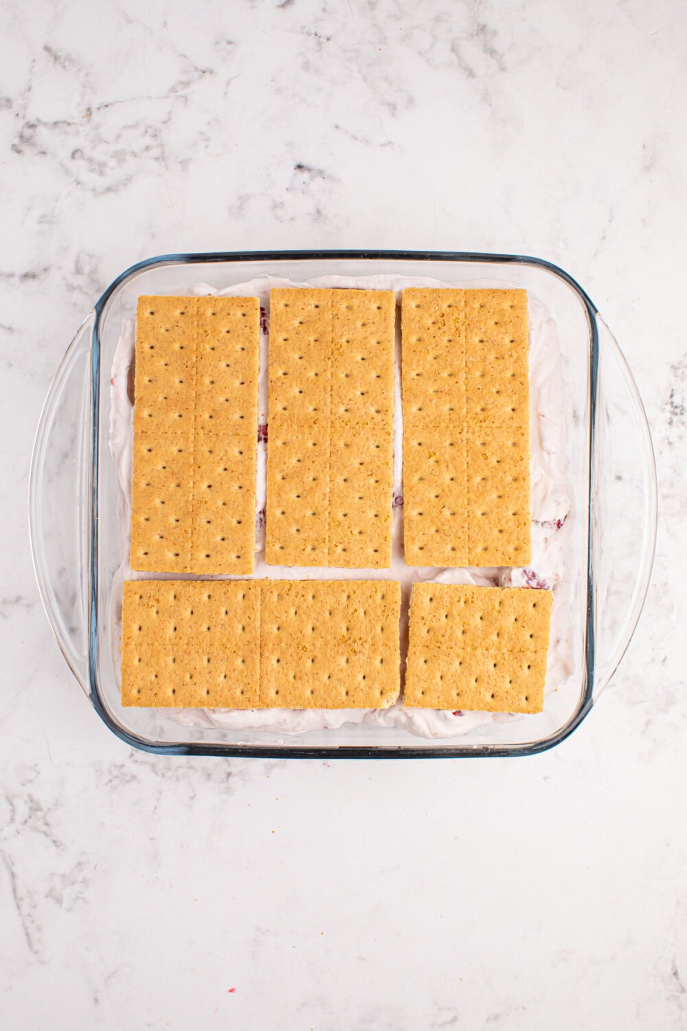 Graham crackers on top of whipped cream in a square dish.