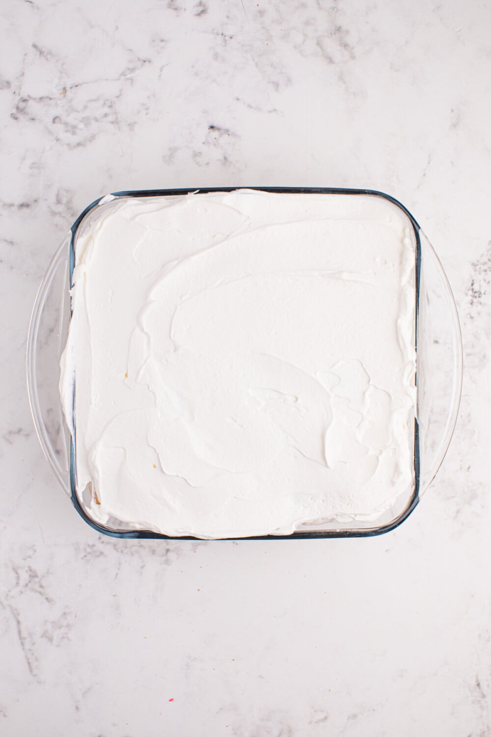 Whipped cream on top of icebox cake in a glass dish.
