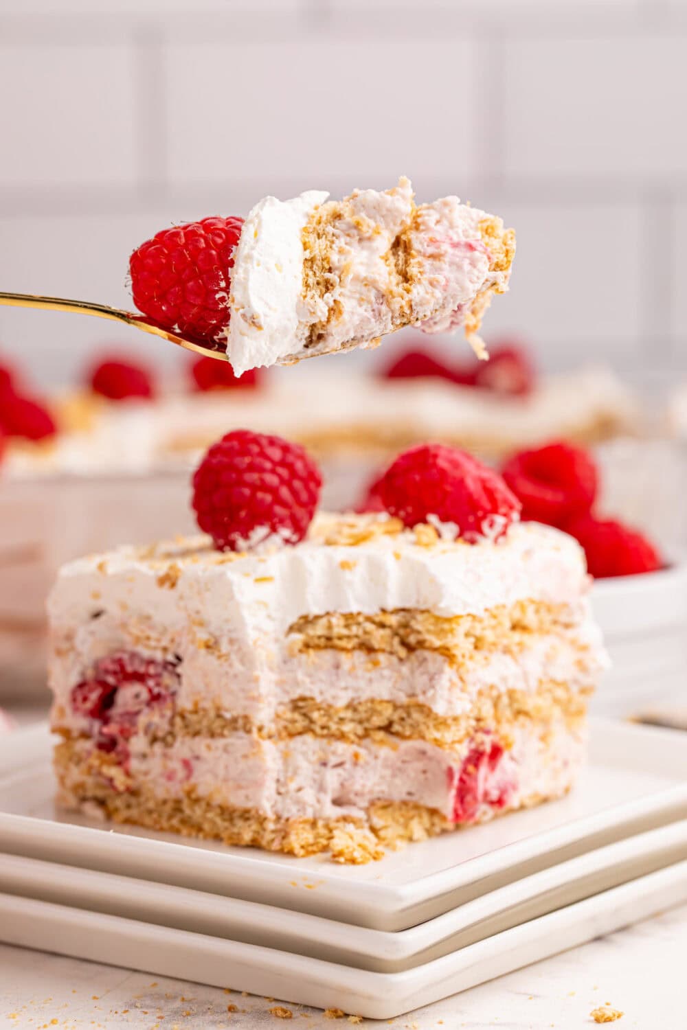 A fork full of raspberry cream icebox cake with the rest of the slice on a plate.