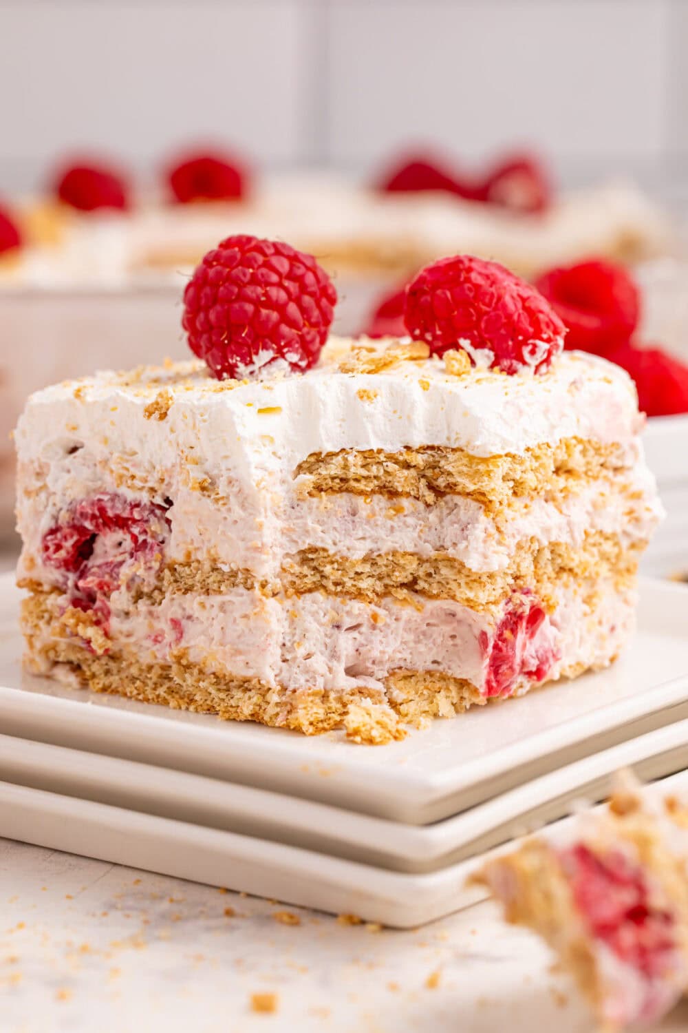 Slice of raspberry cream cake on a plate with a fork bite missing from it.