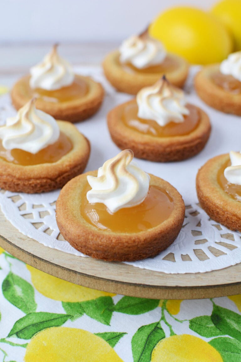 Plate of lemon meringue pie cookies with a lemon in the background.