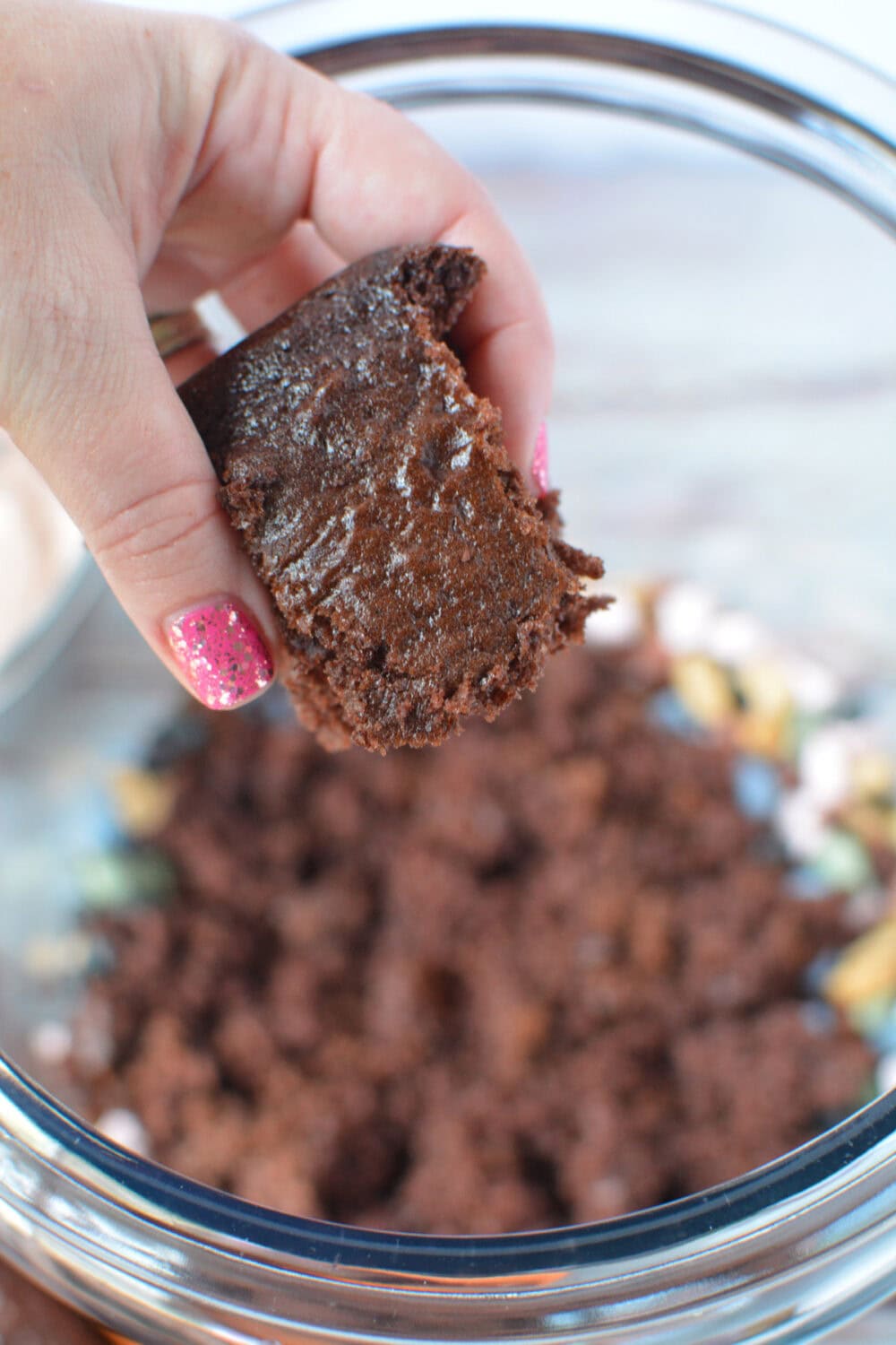 Hand holding chocolate cake over a glass jar