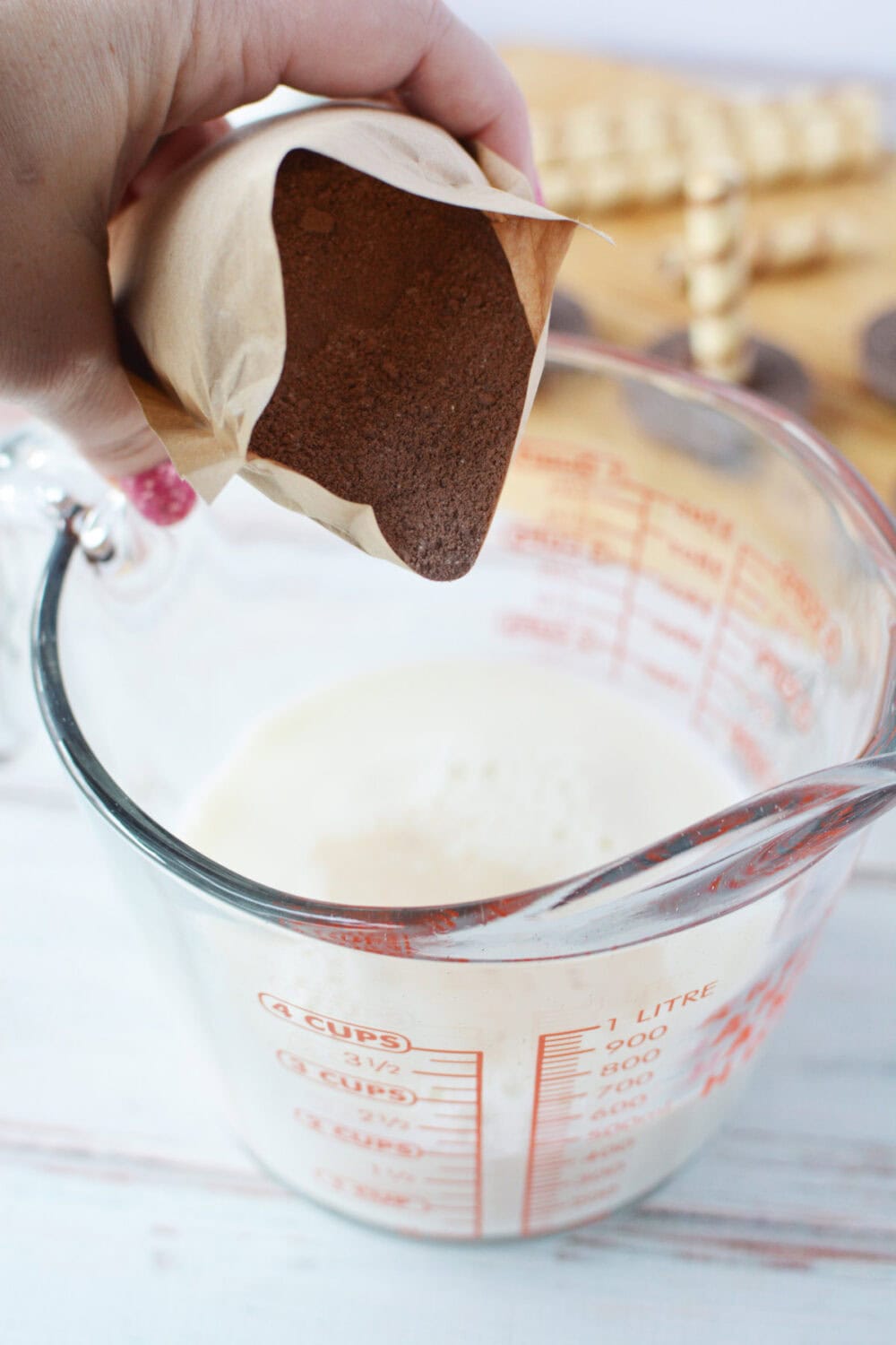 a person pouring a brown powder into a glass cup