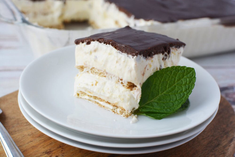 Layered chocolate ice box cake on a plate topped with chocolate ganache.